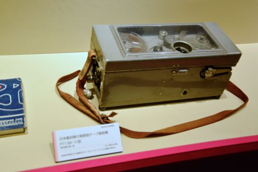 日本最初期の肩掛型テープ録音機　PT1（M-1）型 放送局で愛用された肩掛け式のテープレコーダー。デンスケの愛称の始まり。 「日本最初期」最初の頃と言いたいのでしょうが、おもしろい言葉をつくり出しています。