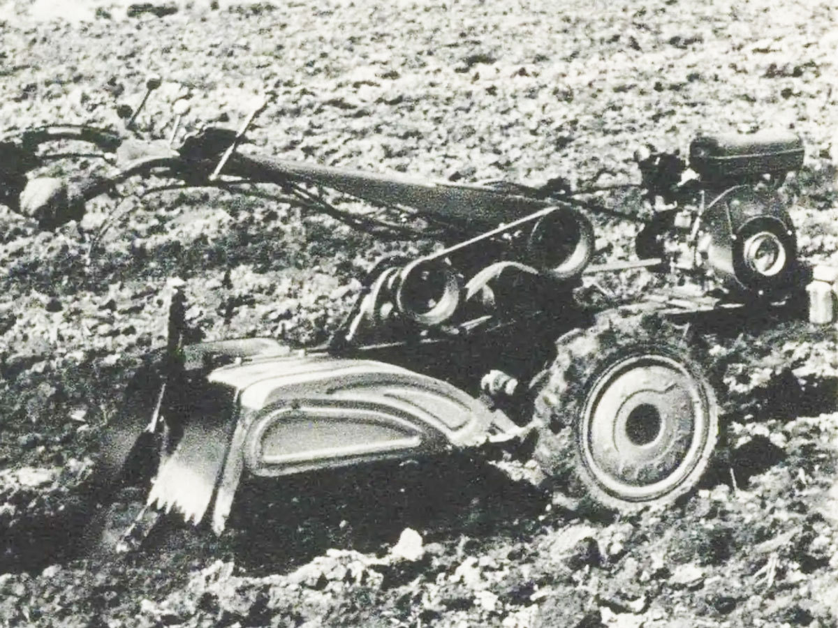 耕運機だけ拡大します。本文には写真はクイーンハンドトラクターK-1型(高知県南国市里改田協和農機株式会社製造)の耕転作業である。 本機は牽引型(テイラー型)と駆動型(ロータリー型)性能の長所をとり合わせた理想的な牽引駆動兼用の万能機で、ロータリー耕起・犂耕・中耕・砕士・畝立・整地・代搔・麦士入・薬剤散布・運搬乗用その他管理作業並に定置作業の照明、動力源等あらゆる作業に最高能率を発揮する万能型である。とあります。