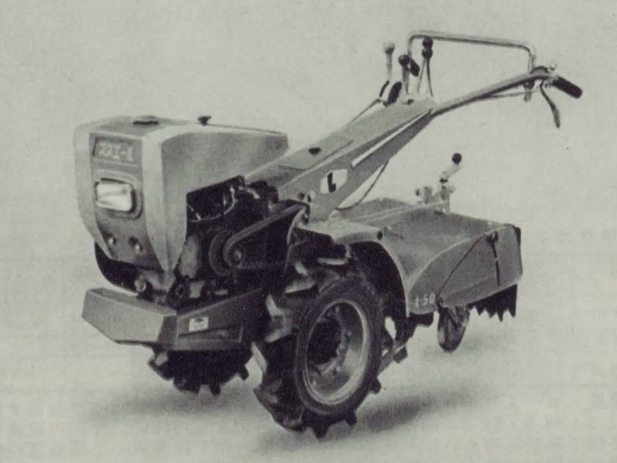 写真を拡大します。エンジンやハンドル根本部分に大きめの四角いカバーをただ掛けたような形。「初めの頃感」がプンプンします。おでこに大きく「スズエ-L」と書かれていますし大きく無骨なハンドルネックのカバーにもでっかく「L」と書かれているのがわかります。